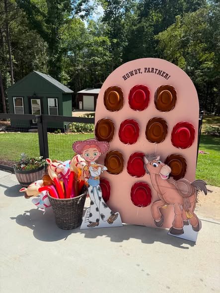 Pink Howdy Partner cowboy hat wall with Jessie and Bullseye cutouts at a Toy Story birthday party