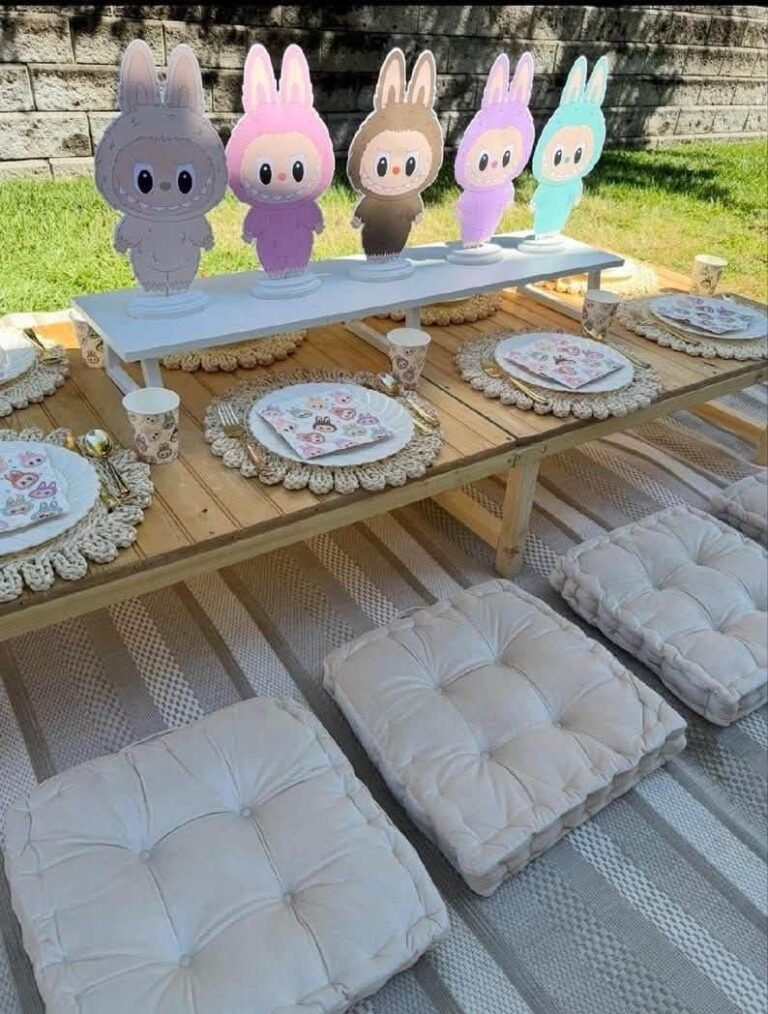 Low picnic party table with Labubu cutouts, floor cushions and pastel plates