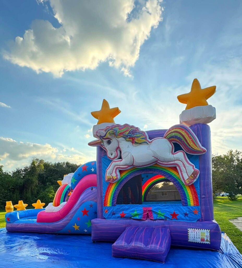 Purple unicorn bounce house with a rainbow and stars in a backyard