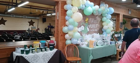 Mint and sage balloon arch in a hall with the dessert table and guests