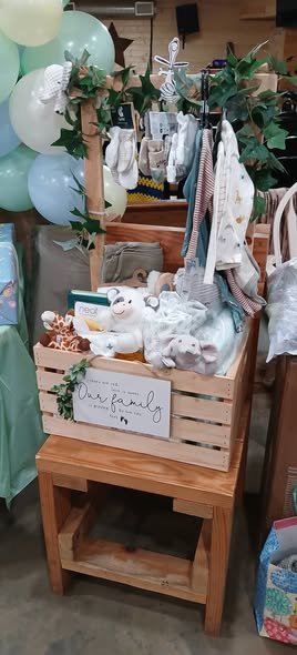 Wooden crate stand with hanging baby clothes, bibs and gifts at a Little Peanut baby shower