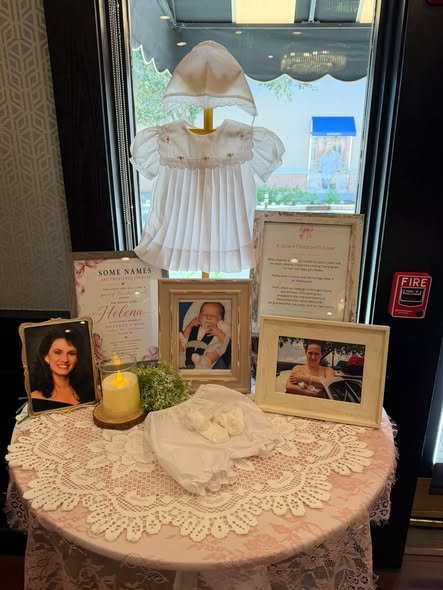 Memory table with framed family photos, a christening gown and a candle