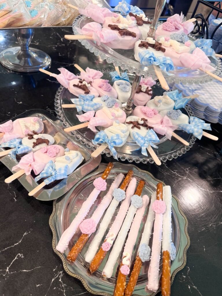Pink and blue horse cake pops and chocolate dipped pretzels on glass trays
