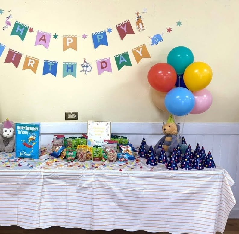 Party Animal 1st birthday table with an animal Happy Birthday banner, rainbow balloons and party hats