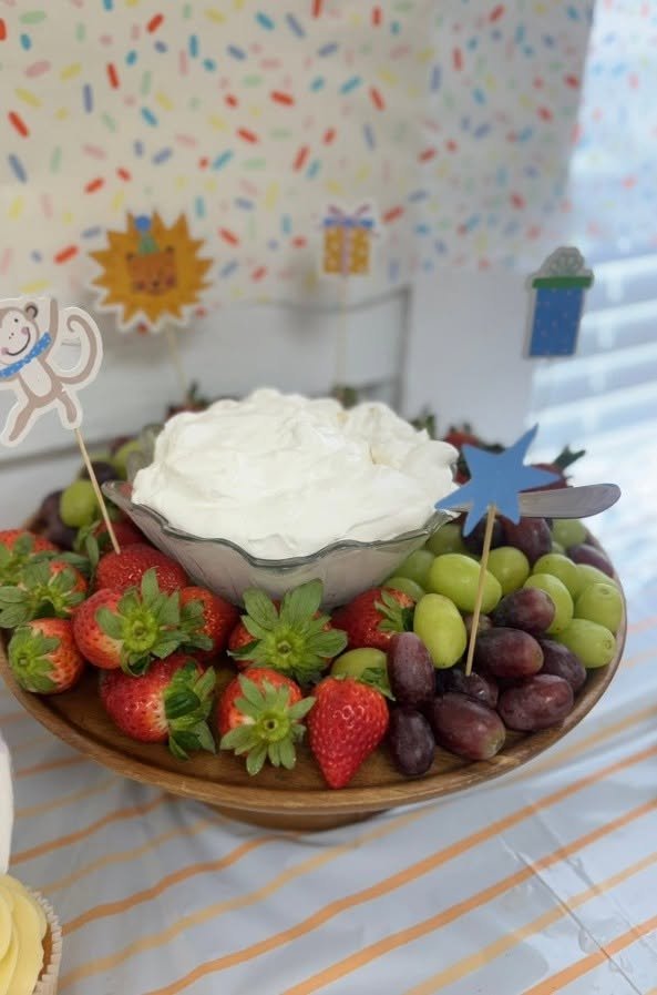 Fruit bowl with strawberries and grapes and a bowl of dip with animal picks