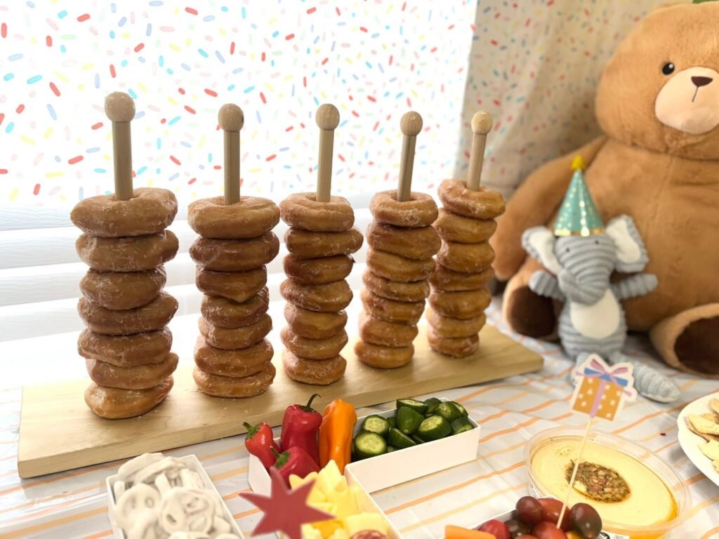 Bagel tower on a wood stand next to a plush elephant in a party hat