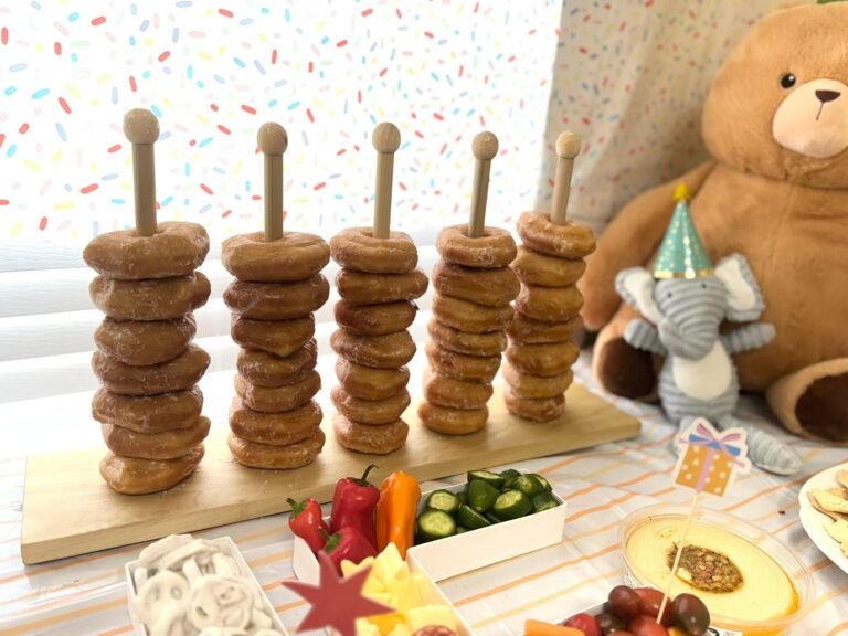 Bagel tower on a wood stand next to a plush elephant in a party hat