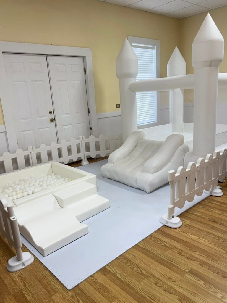 White soft play area with a ball pit, slide and white fence for a 1st birthday