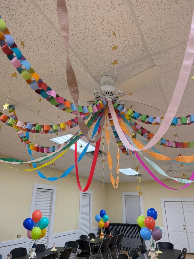 Rainbow paper chains and streamers hanging from the ceiling at a 1st birthday party