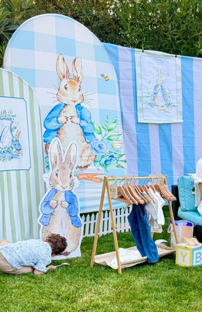 Peter Rabbit cutouts on a blue gingham backdrop with a baby clothes rack