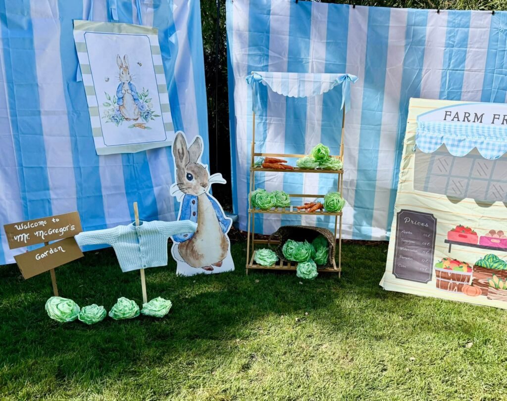 Wide view of a Peter Rabbit baby shower with blue striped walls and a farm stand
