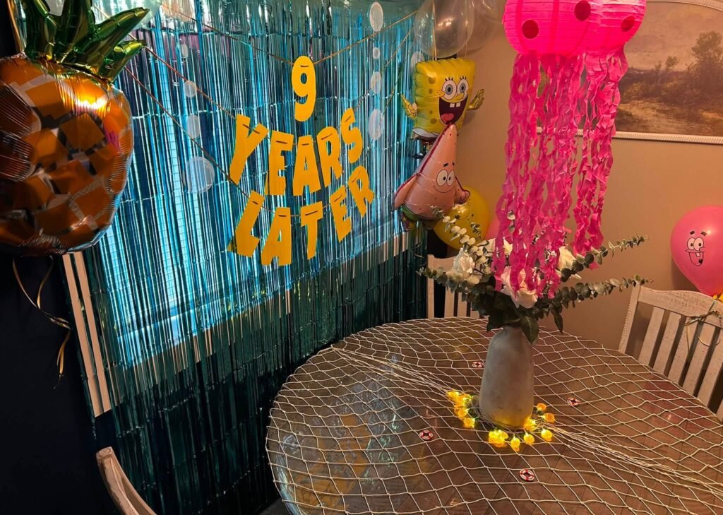9 Years Later SpongeBob backdrop with blue fringe curtain, pineapple balloon and pink jellyfish lantern
