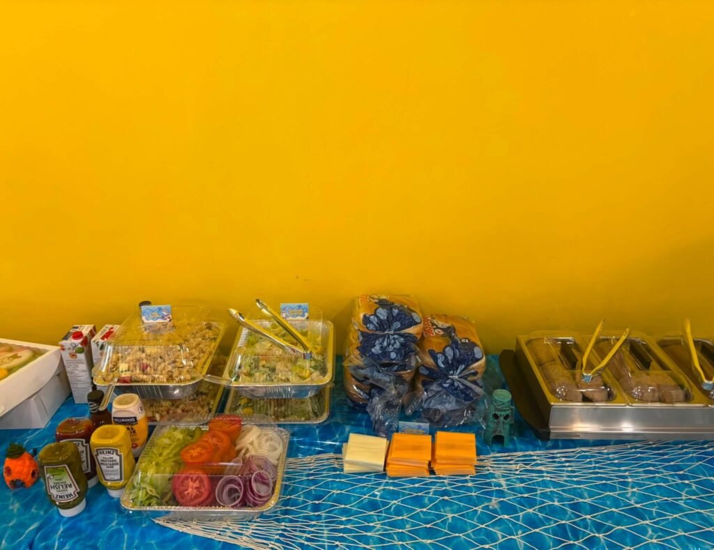 SpongeBob party snack table with sandwiches, fruit and drinks against a yellow wall