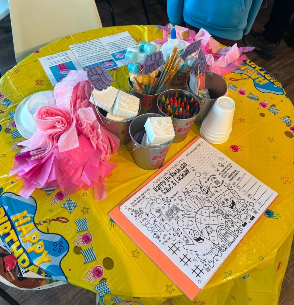 Kids craft table with SpongeBob coloring sheets, crayons and paper flowers