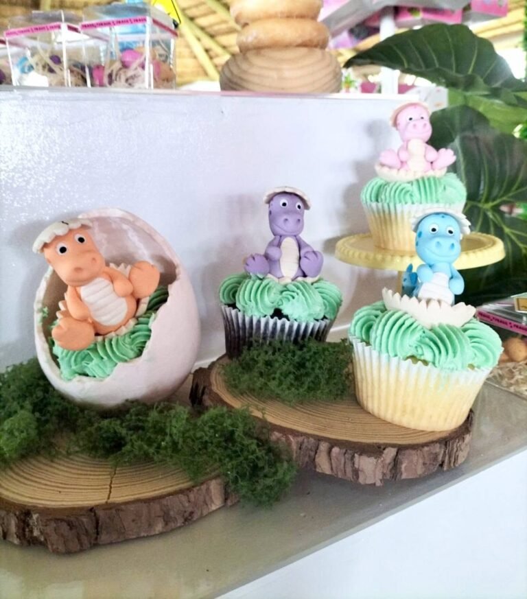 Hatching dinosaur egg cupcake with a baby dino topper and green grass frosting