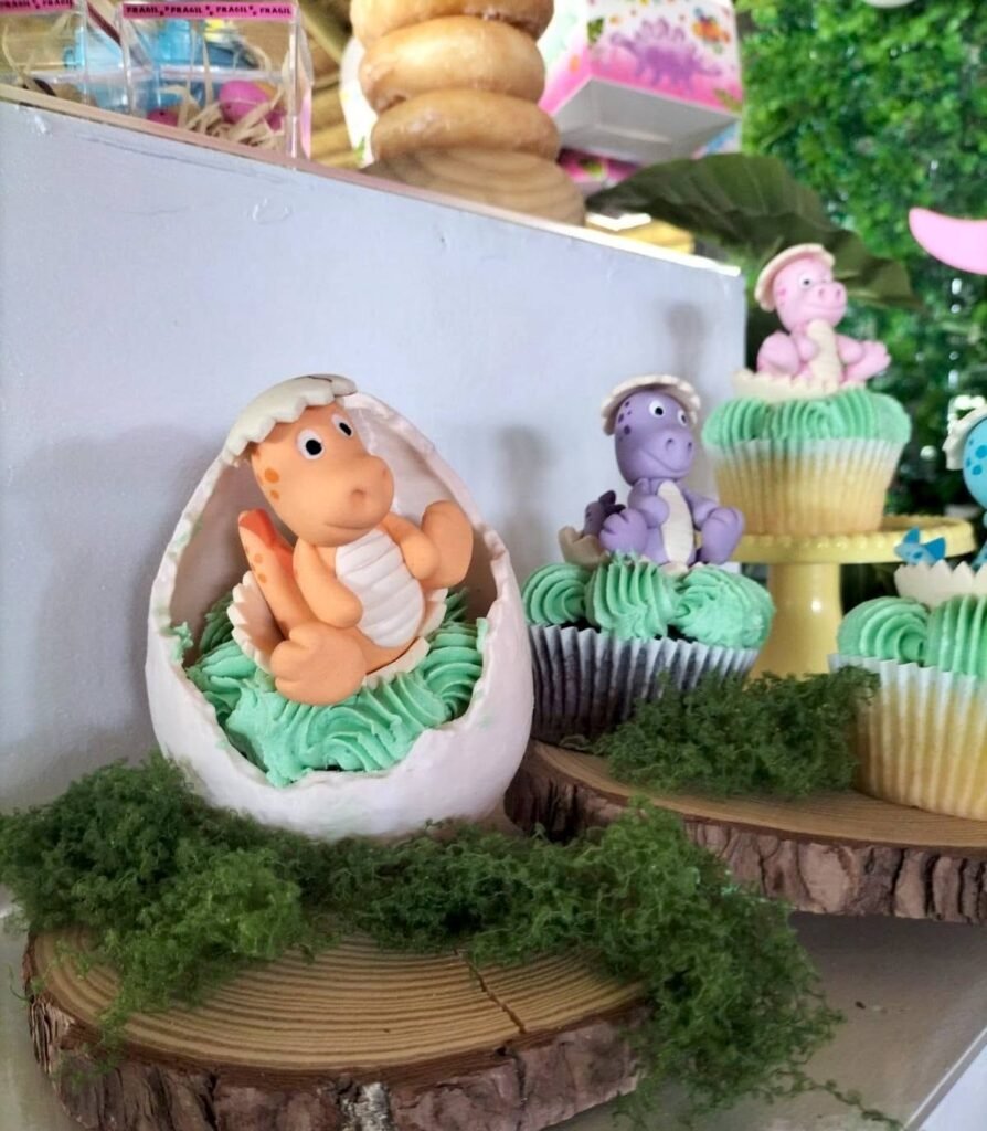 Dino egg cupcake display on wood slices with moss and a purple dinosaur topper