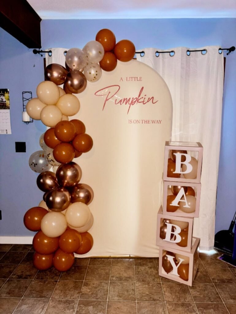 Little Pumpkin baby shower arch backdrop with a rust, cream and copper chrome balloon garland and BABY blocks at home