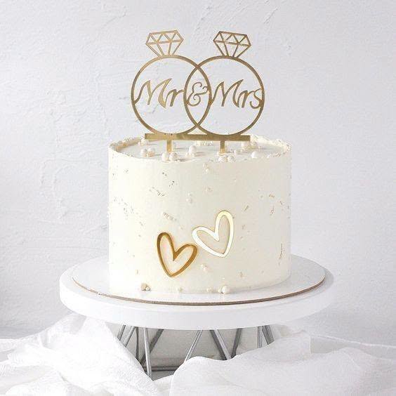 White one tier wedding cake with a gold Mr and Mrs ring topper and gold hearts