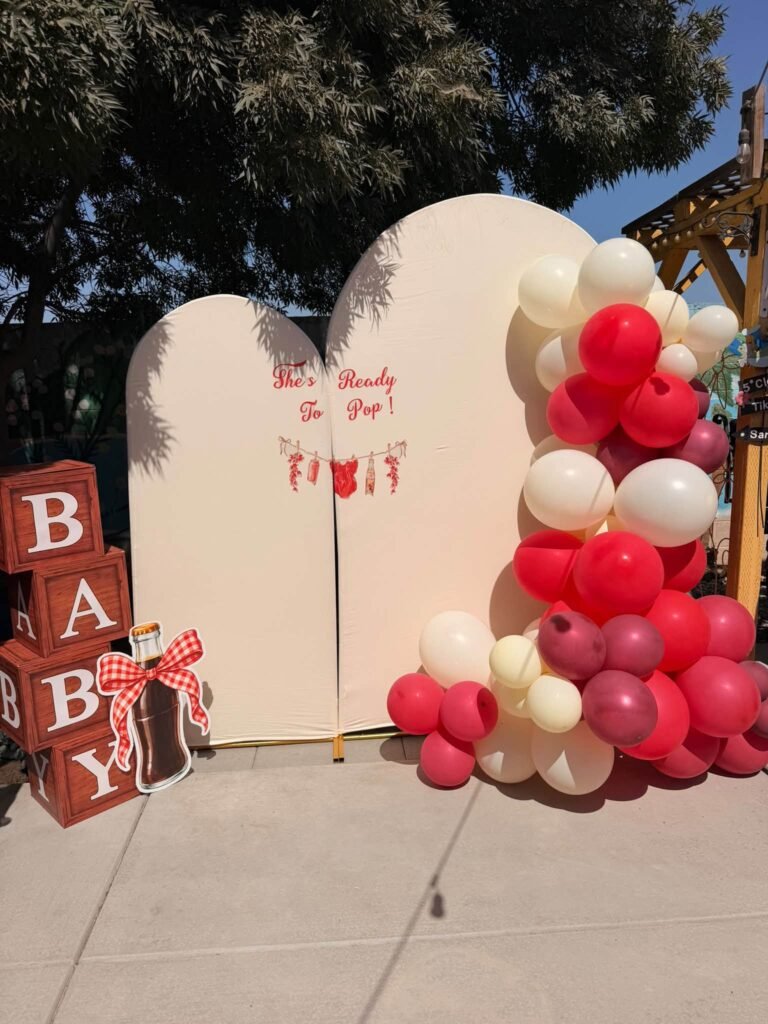 Ready to Pop baby shower backdrop with white arches, red and white balloons and red BABY blocks