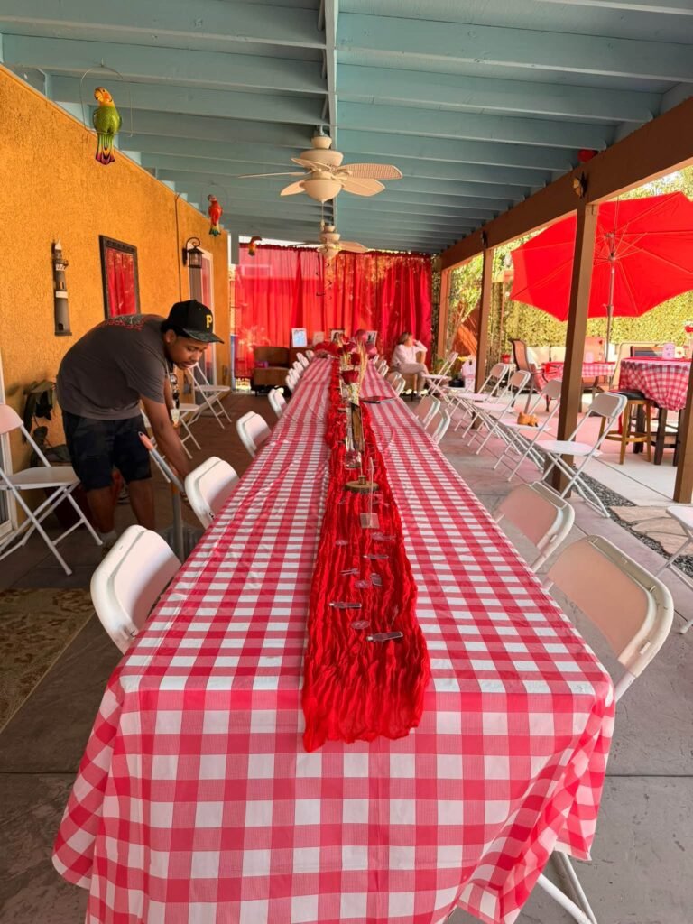 Long red gingham table being set up on a covered patio for a Ready to Pop shower