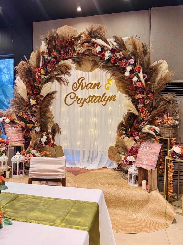 Front view of a rustic pampas grass wedding arch with lanterns and a green runner