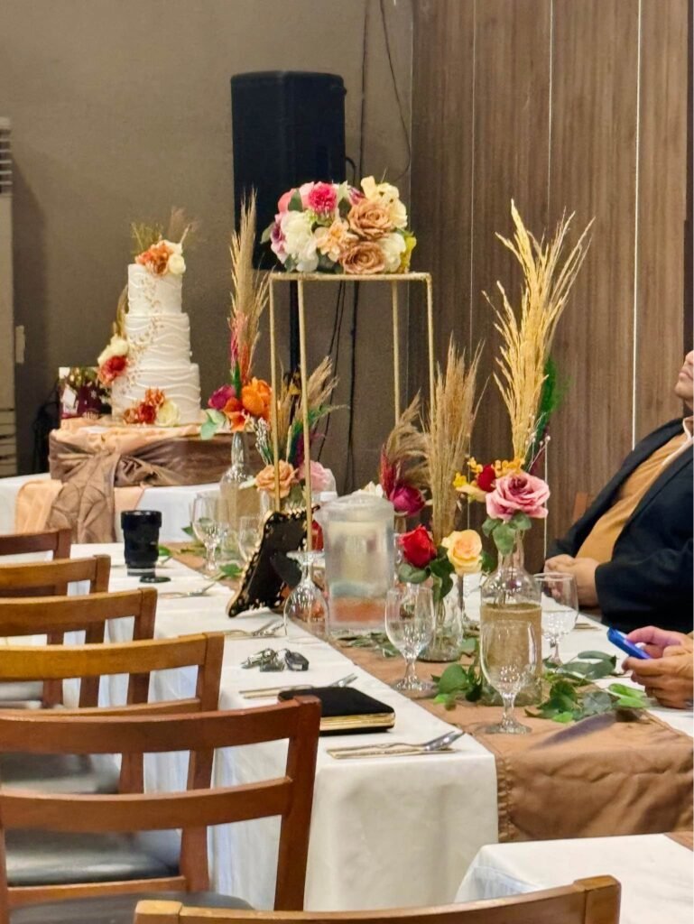 Rustic wedding reception table with pampas grass, orange roses and a tall gold flower stand