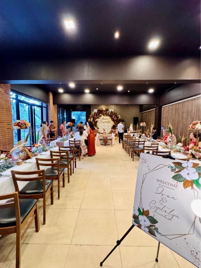 Wedding welcome sign with watercolor flowers on an easel at the entrance of a rustic reception