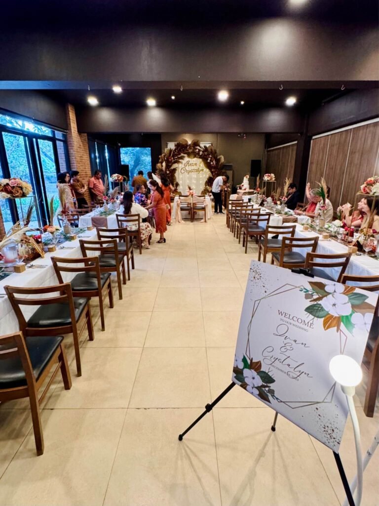 Rustic wedding reception room with long tables, guests and a floral welcome sign