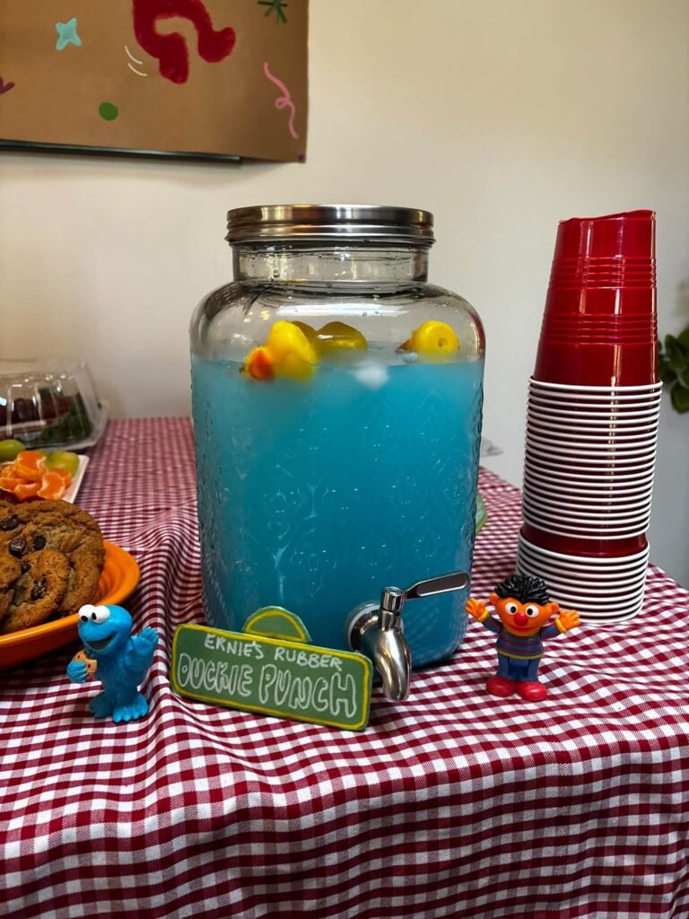 Blue punch in a drink dispenser with rubber ducks and red cups