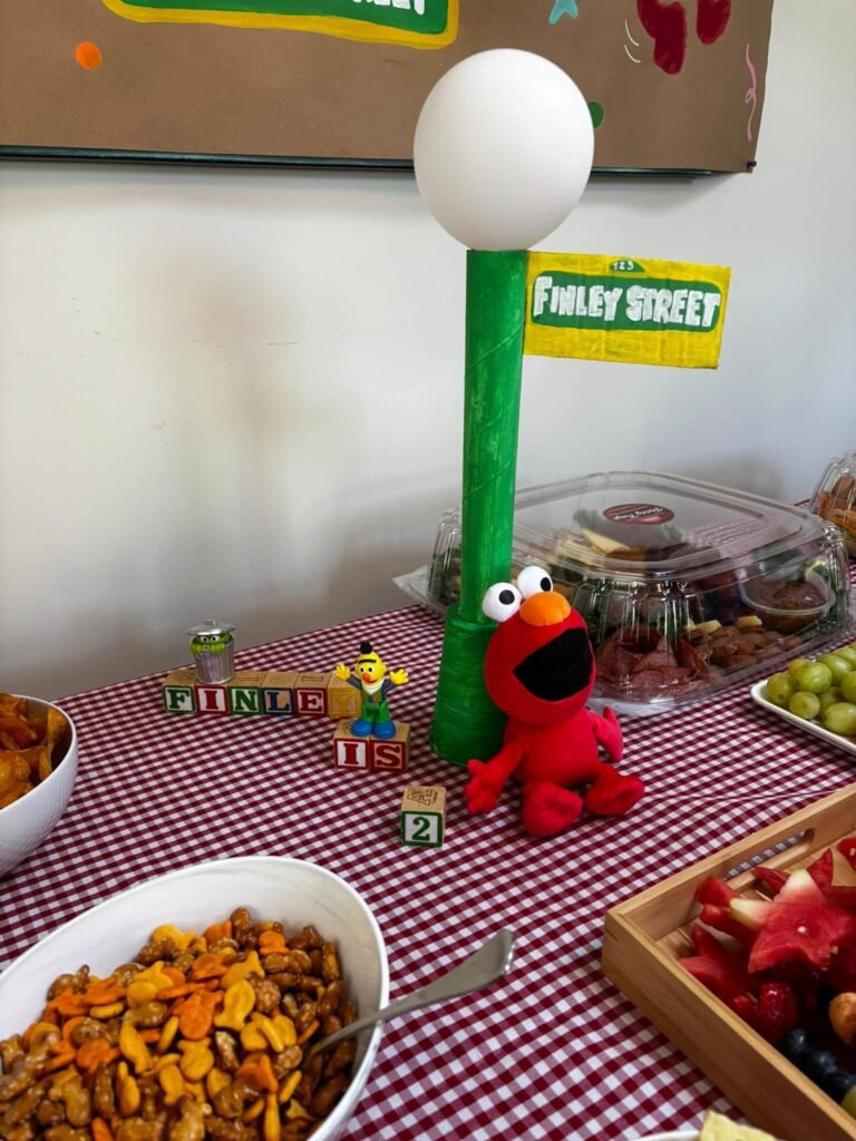 Sesame Street street sign on a lamp post with Elmo and snacks