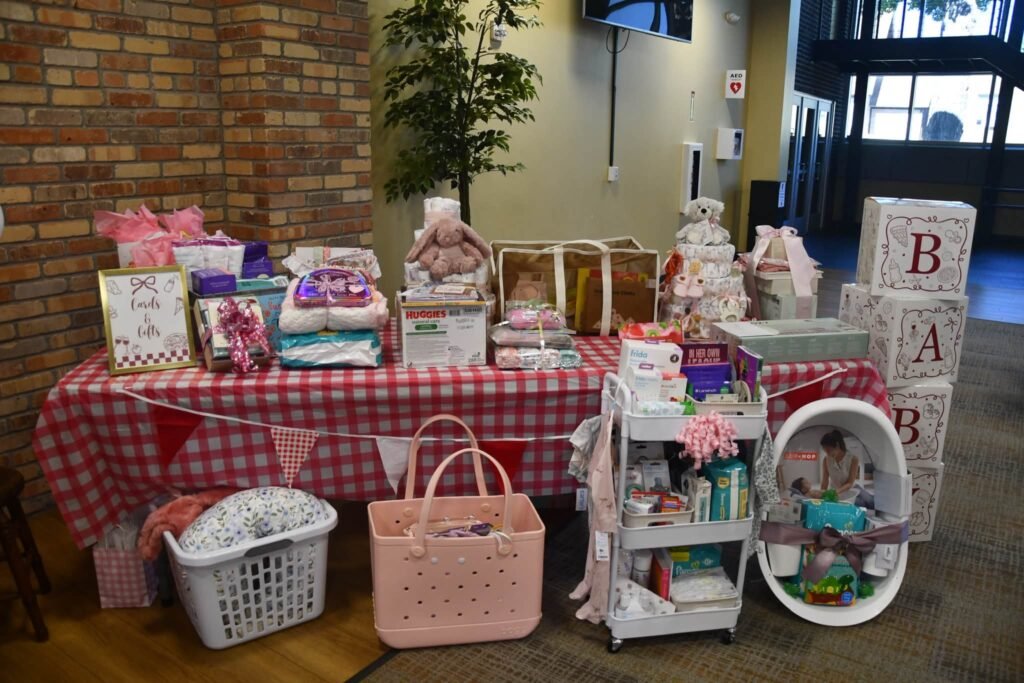 Baby shower gift table with a red gingham tablecloth, pennant bunting, BABY blocks and gifts