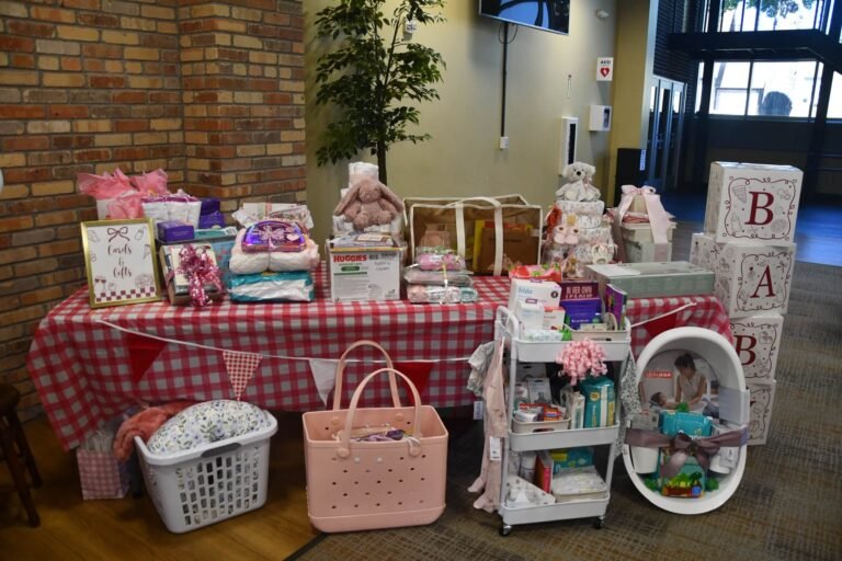 Baby shower gift table with a red gingham tablecloth, pennant bunting, BABY blocks and gifts
