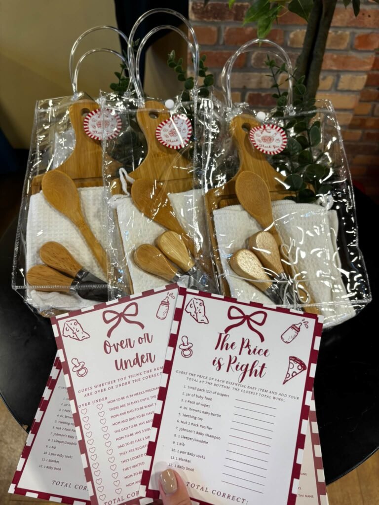 Baby shower game prizes in clear bags with wooden cheese boards and printable Over or Under and The Price is Right games