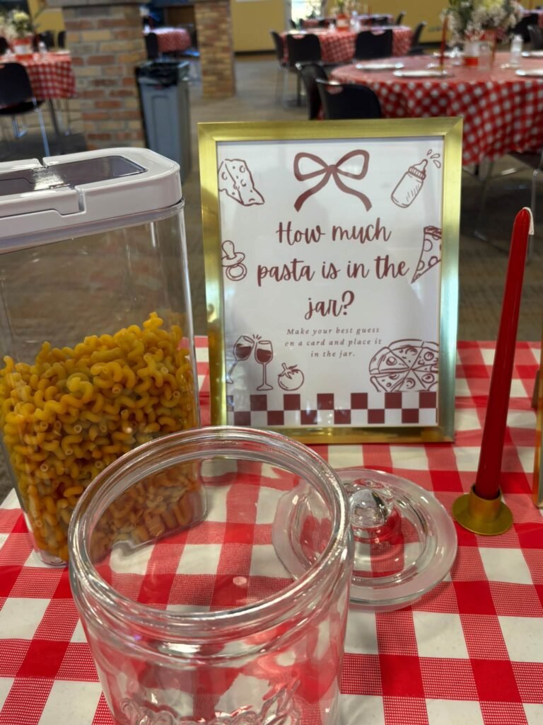 How much pasta is in the jar baby shower guessing game sign in a gold frame next to a jar of pasta
