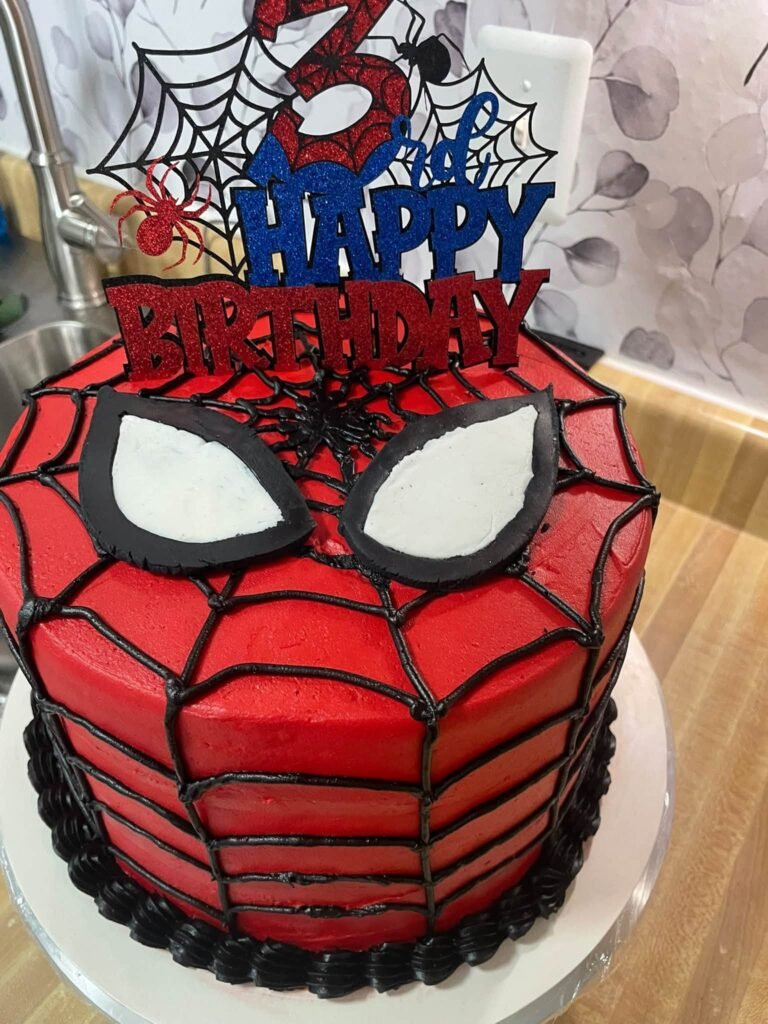 Red Spiderman birthday cake with black web piping, white mask eyes and a glitter number 3 topper