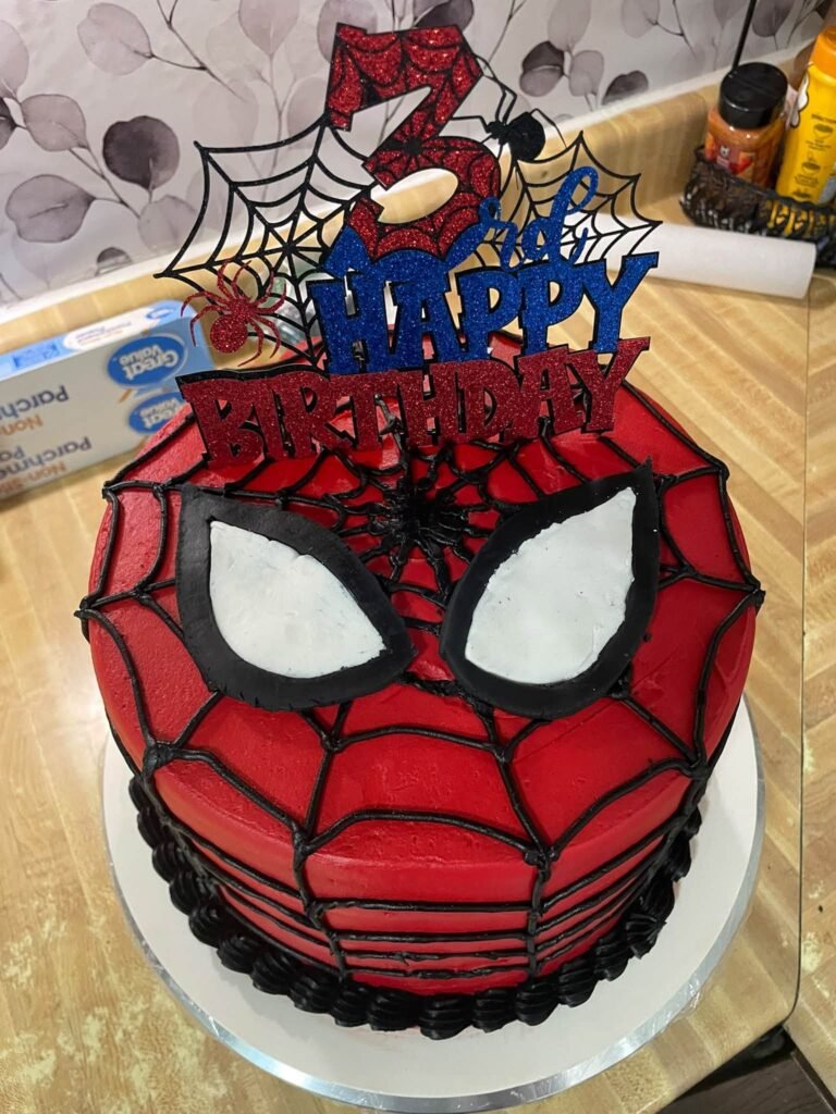 Front view of a Spiderman mask cake with a Happy Birthday 3 topper