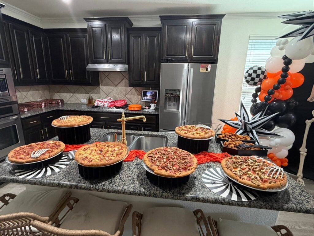 Pizza bar on a kitchen island with several pizzas, black and white striped plates and an orange runner