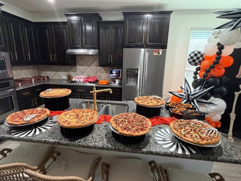 Pizza bar on a kitchen island with several pizzas, black and white striped plates and an orange runner