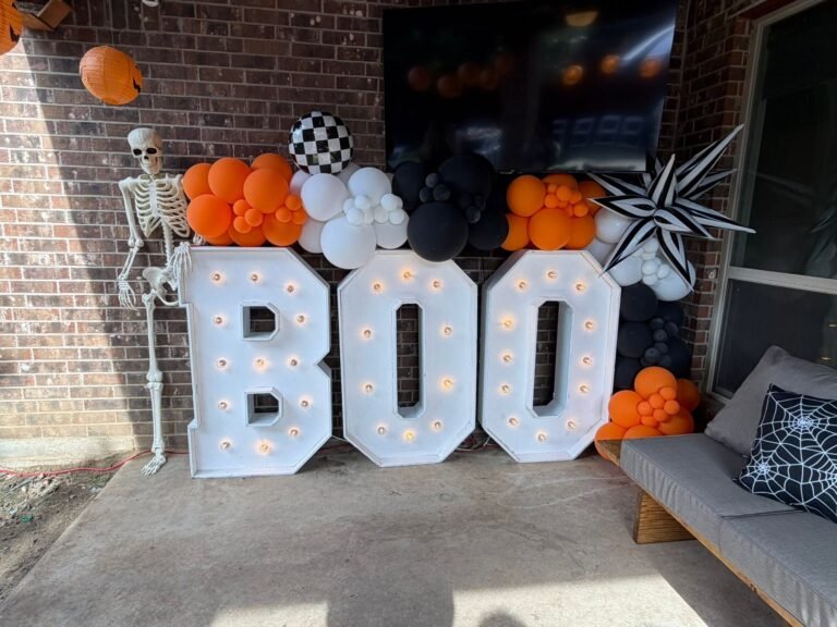 Light up BOO marquee letters on a patio with a skeleton and orange, black and white balloons