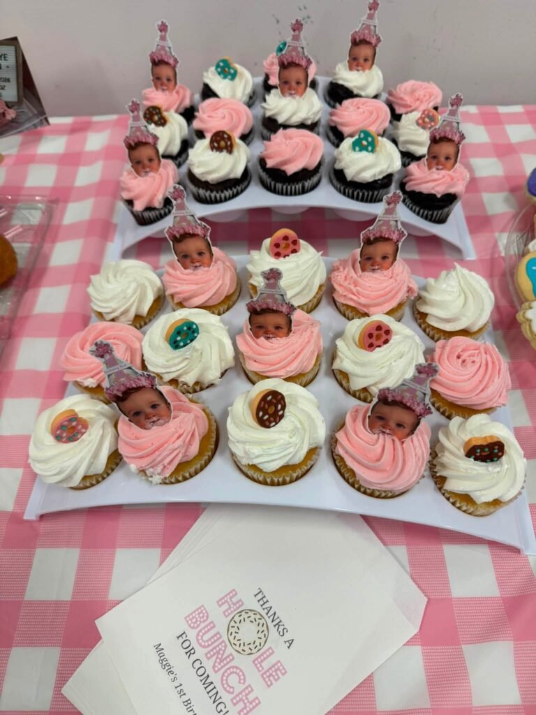 Cupcakes with baby photo toppers on a pink gingham table