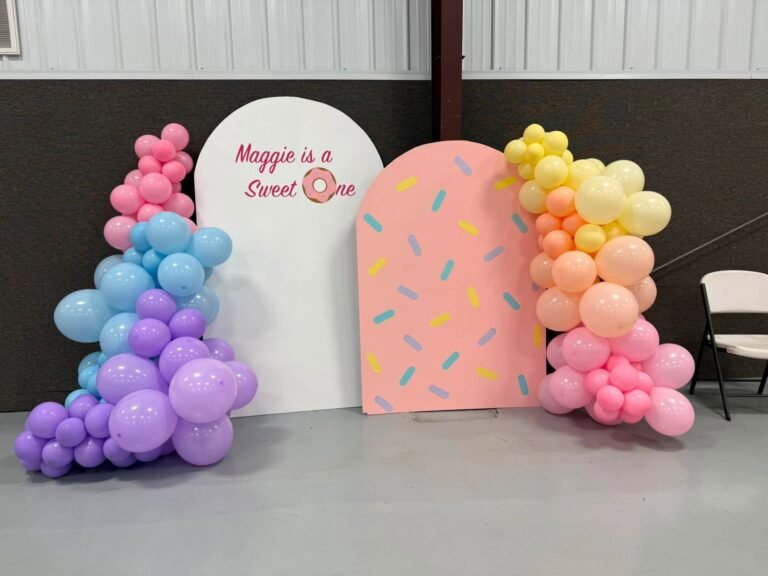 Wide view of a Sweet One donut backdrop with a rainbow balloon garland