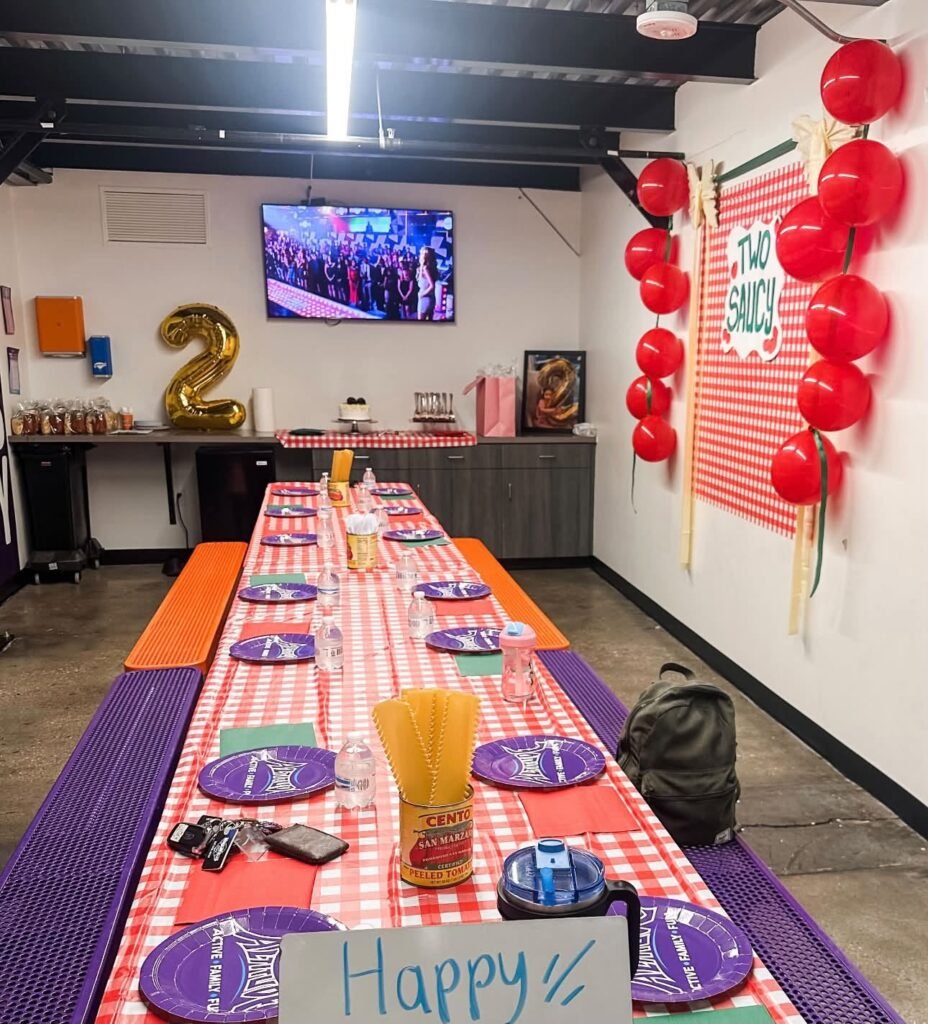 Long red gingham party table with a number 2 balloon and red balloon garland