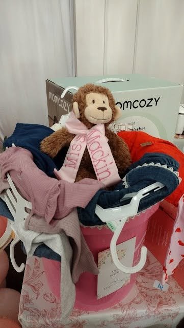 Baby gift basket with a plush monkey, baby clothes and a bottle warmer