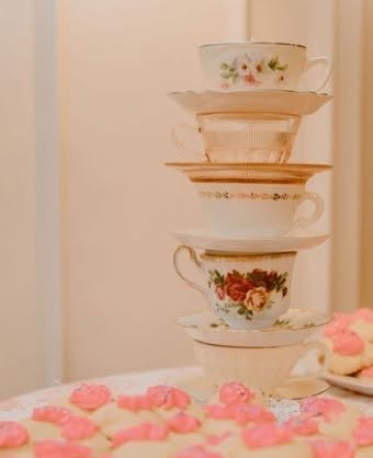Stack of vintage teacups and saucers on a pink table