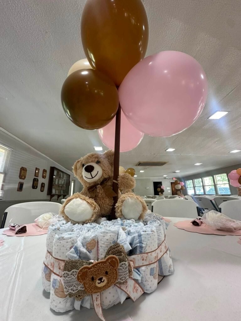 Teddy bear diaper cake centerpiece with pink and brown balloons