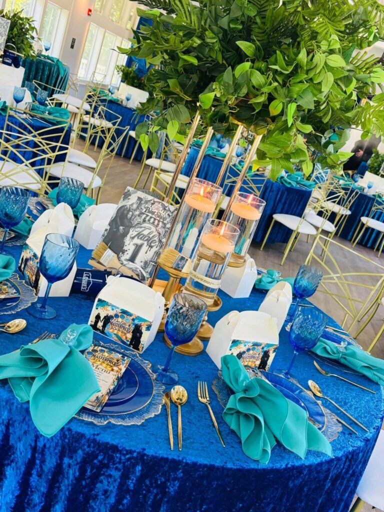 Navy velvet table with teal napkins, gold chargers and a tall centerpiece