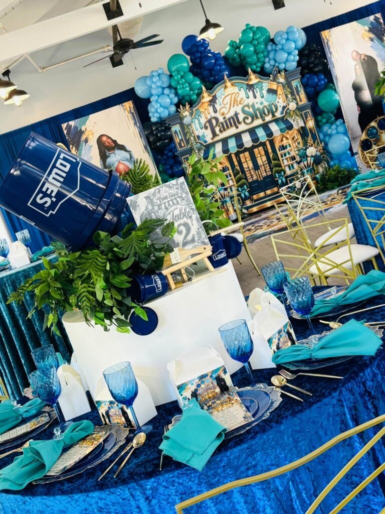 Paint Shop baby shower tables in front of the backdrop with navy and teal decor