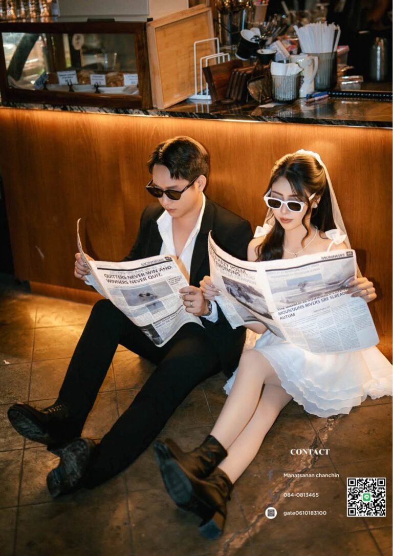 Couple in sunglasses sitting on a cafe floor reading newspapers, bride in a short white dress