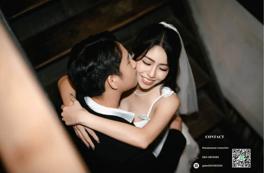 Groom hugging a laughing bride in a short white dress in a dark room