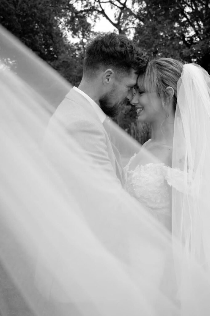 Black and white photo of a couple under a flowing veil